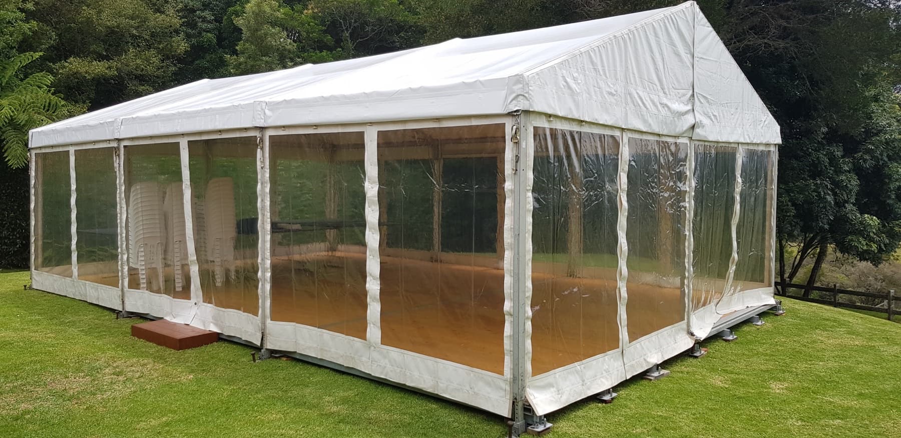 White-roof marquee with clear sidewalls set up on a lawn