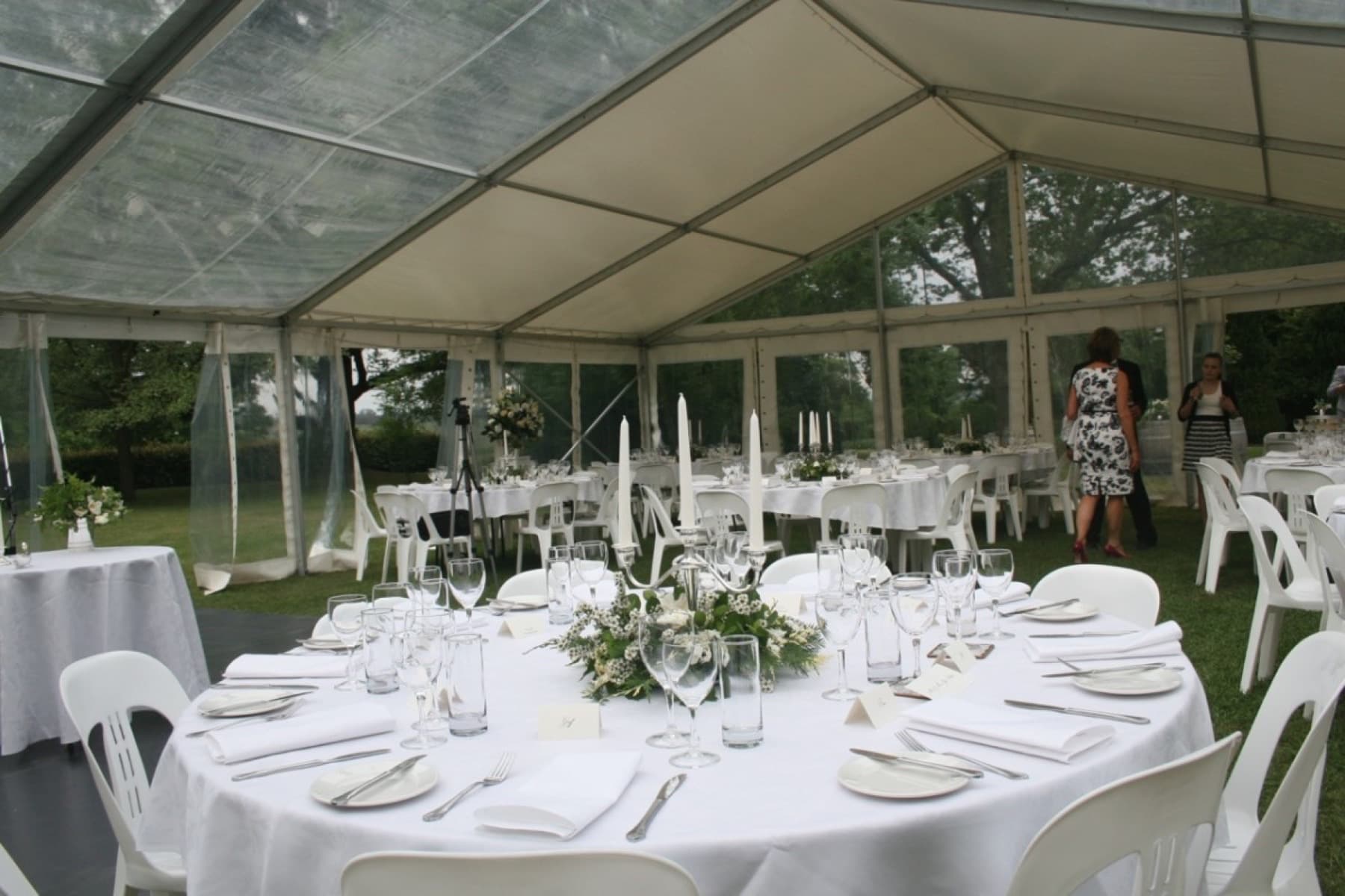 Wedding reception tables set under a clear gable marquee