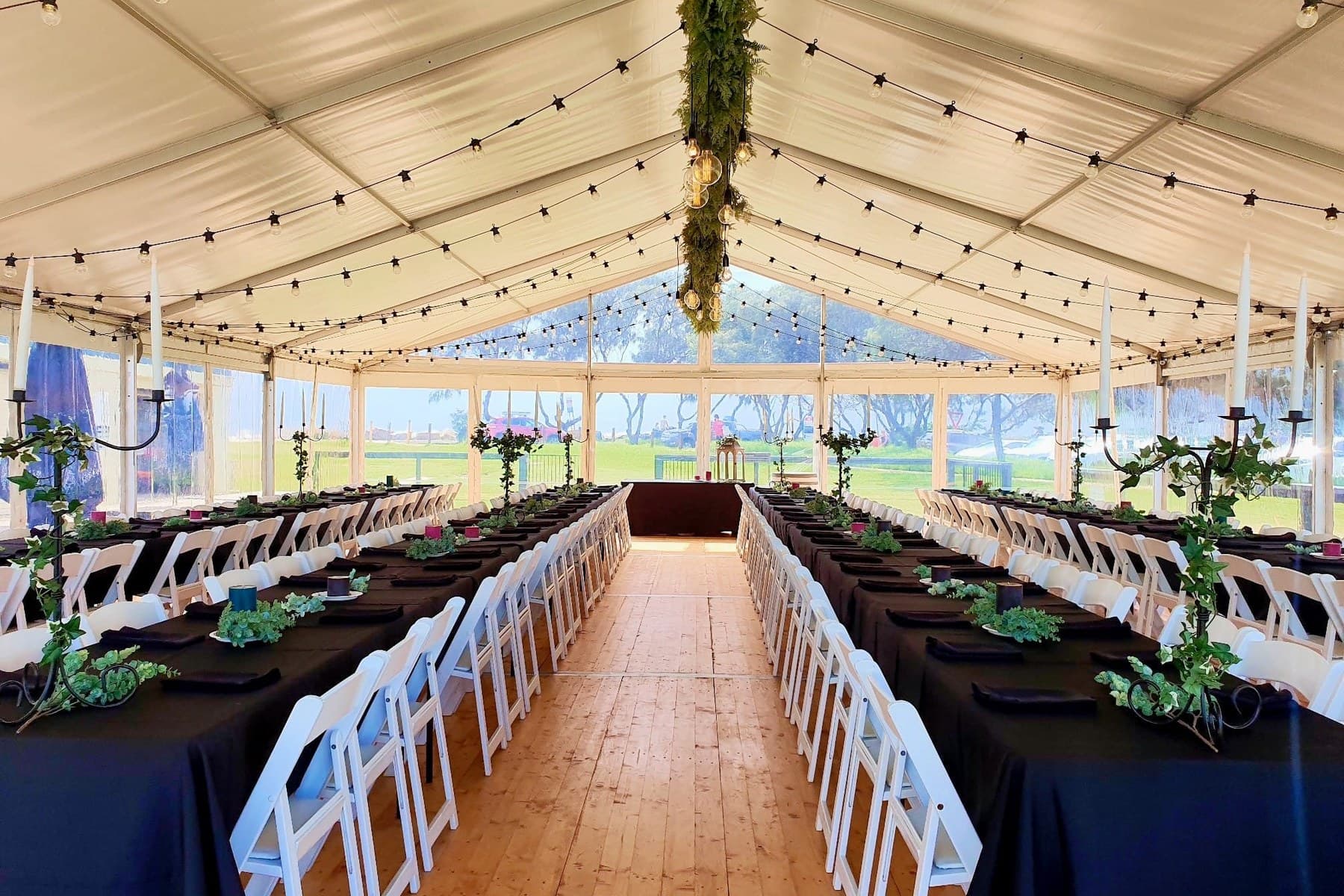 Marquee with timber floor and festoon lighting set with long tables for a seated dinner